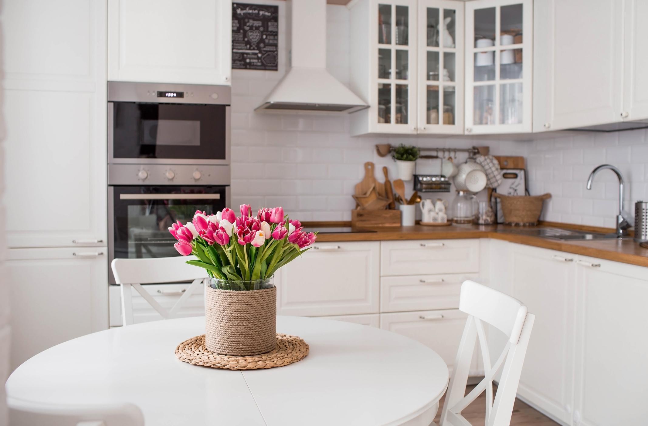 A bouquet of tulips on a white table. In the background, the interior of a white kitchen in the Scandinavian style.